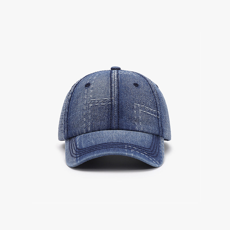 Blue cotton baseball cap shown front-facing with a structured six-panel crown, curved brim, visible seam detailing, and ventilation eyelets.