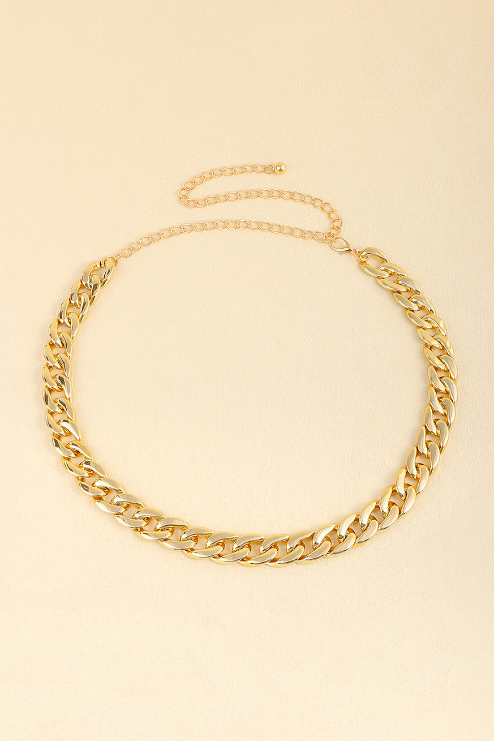 Gold-tone adjustable curb chain belt featuring bold linked construction, a statement waist or hip silhouette, and a slender extension chain for versatile styling.