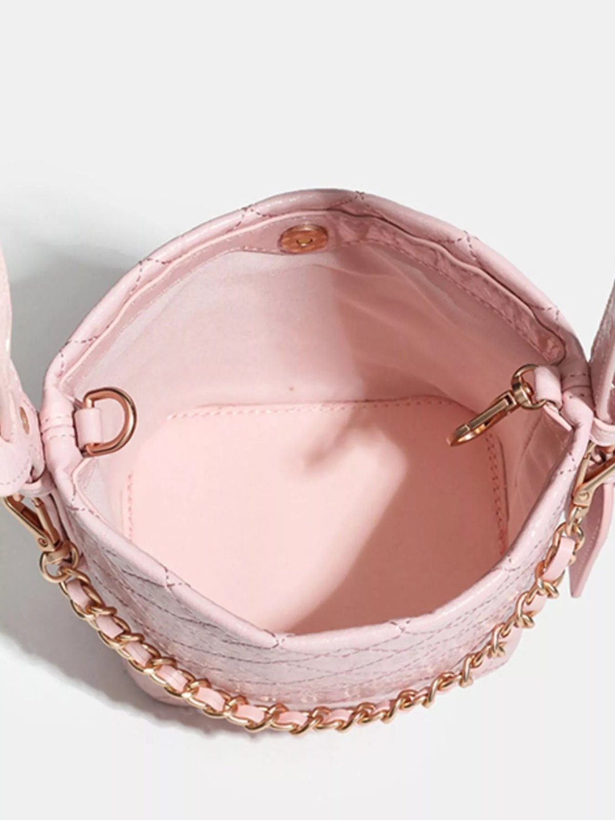 Open small pink PU leather bucket bag showing a spacious interior, stitched construction, gold-tone hardware, and an adjustable strap with chain detailing.