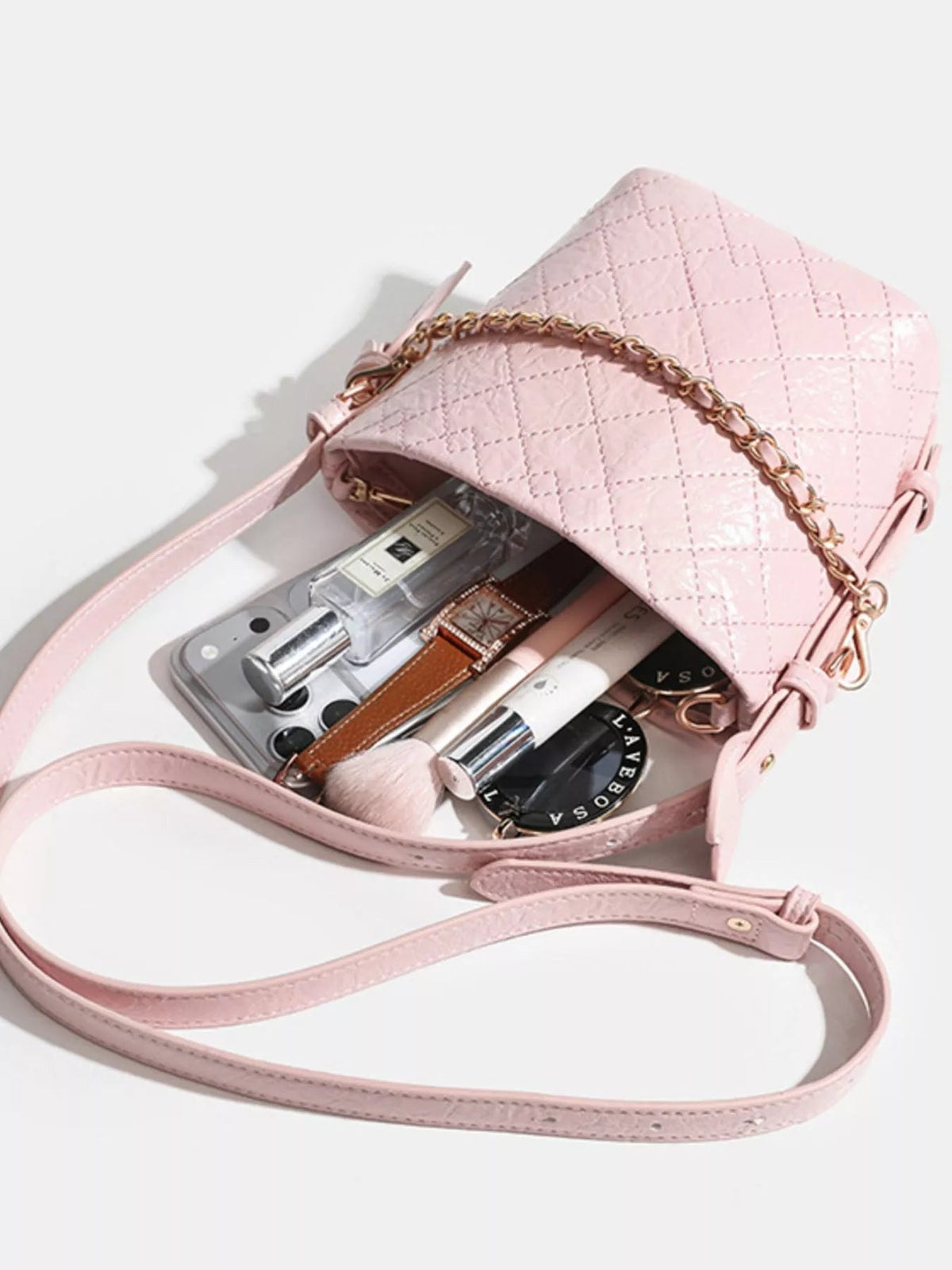 Small pink PU leather bucket bag with quilted construction, an open top, gold-tone chain detail, and a long adjustable strap.