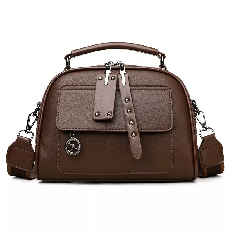 Small brown PU leather crossbody bag with an adjustable shoulder strap, top handle, structured silhouette, front pocket, and dual zipper closure.