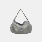 A large light-wash denim tote bag with a softly curved silhouette, adjustable shoulder strap, and visible seamed construction.