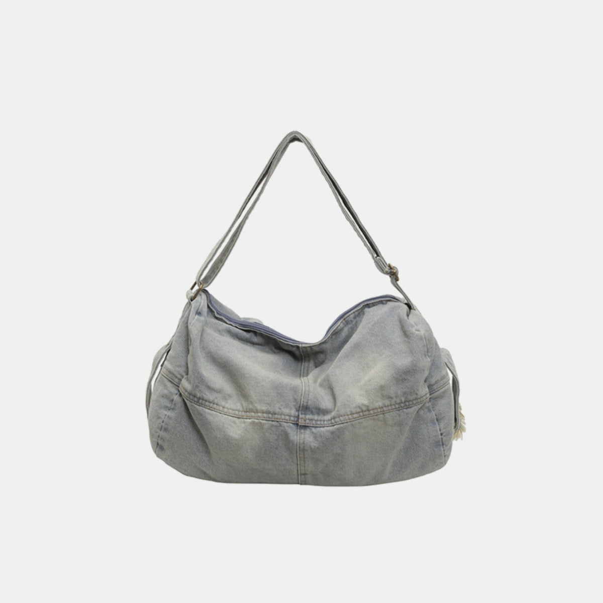 A large light-wash denim tote bag with a softly curved silhouette, adjustable shoulder strap, and visible seamed construction.