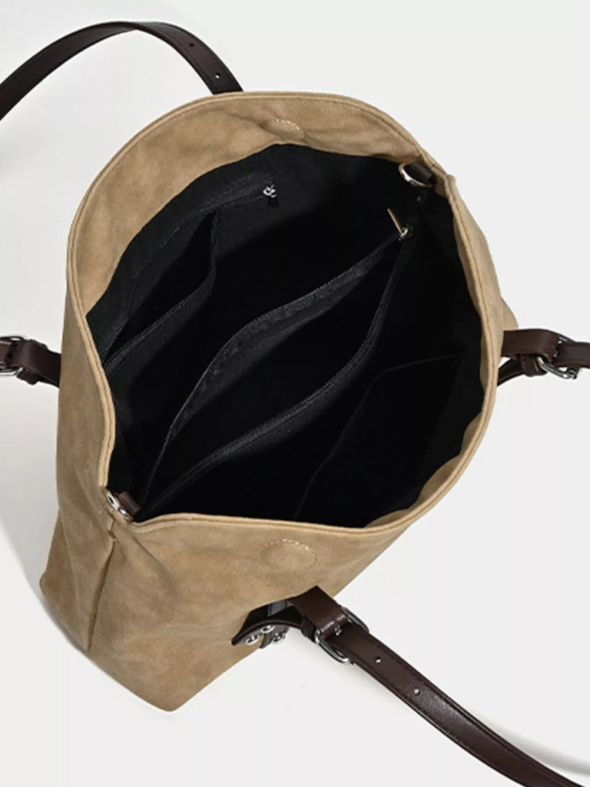 Medium tan suede shoulder bag shown open with a black lined interior, multiple compartments, and an adjustable dark brown strap with metal hardware.