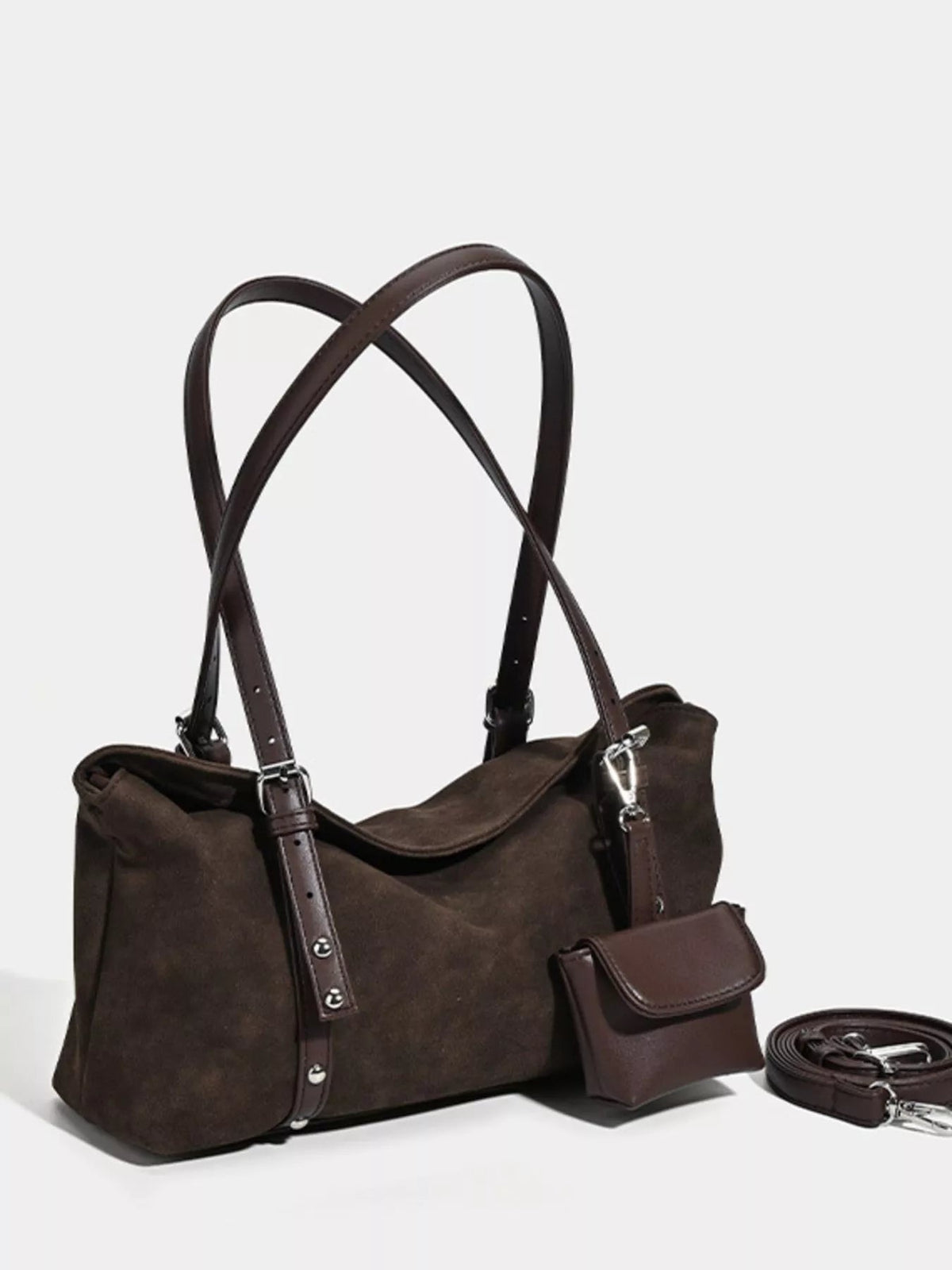 A medium dark brown suede shoulder bag features dual handles, an adjustable detachable strap, silver-tone hardware, and a relaxed soft-sided silhouette.