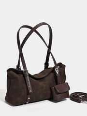 A medium dark brown suede shoulder bag features dual handles, an adjustable detachable strap, silver-tone hardware, and a relaxed soft-sided silhouette.