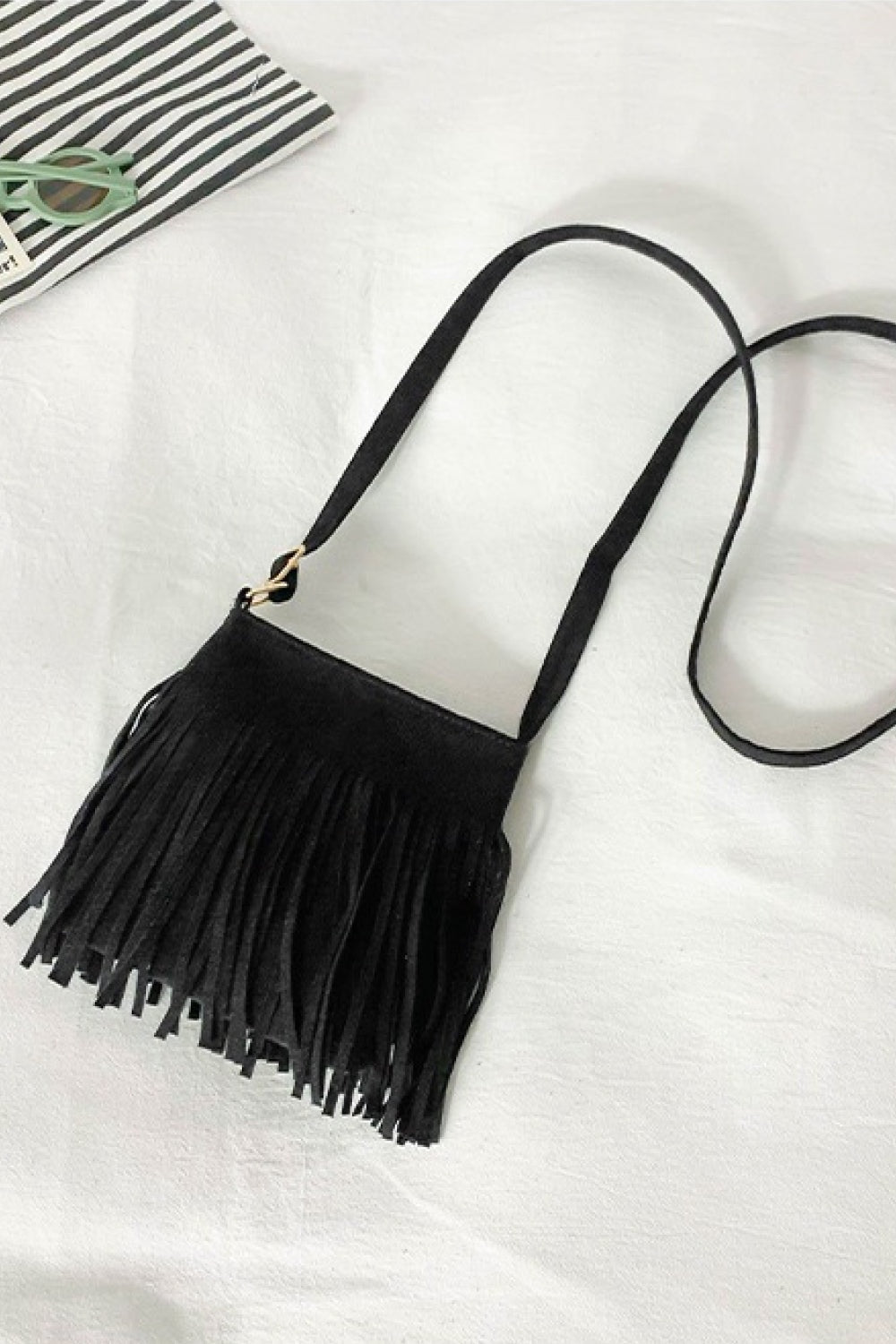 Black PU leather crossbody bag with a compact rectangular sling silhouette, long fringe detailing, a slim strap, and gold-tone hardware.