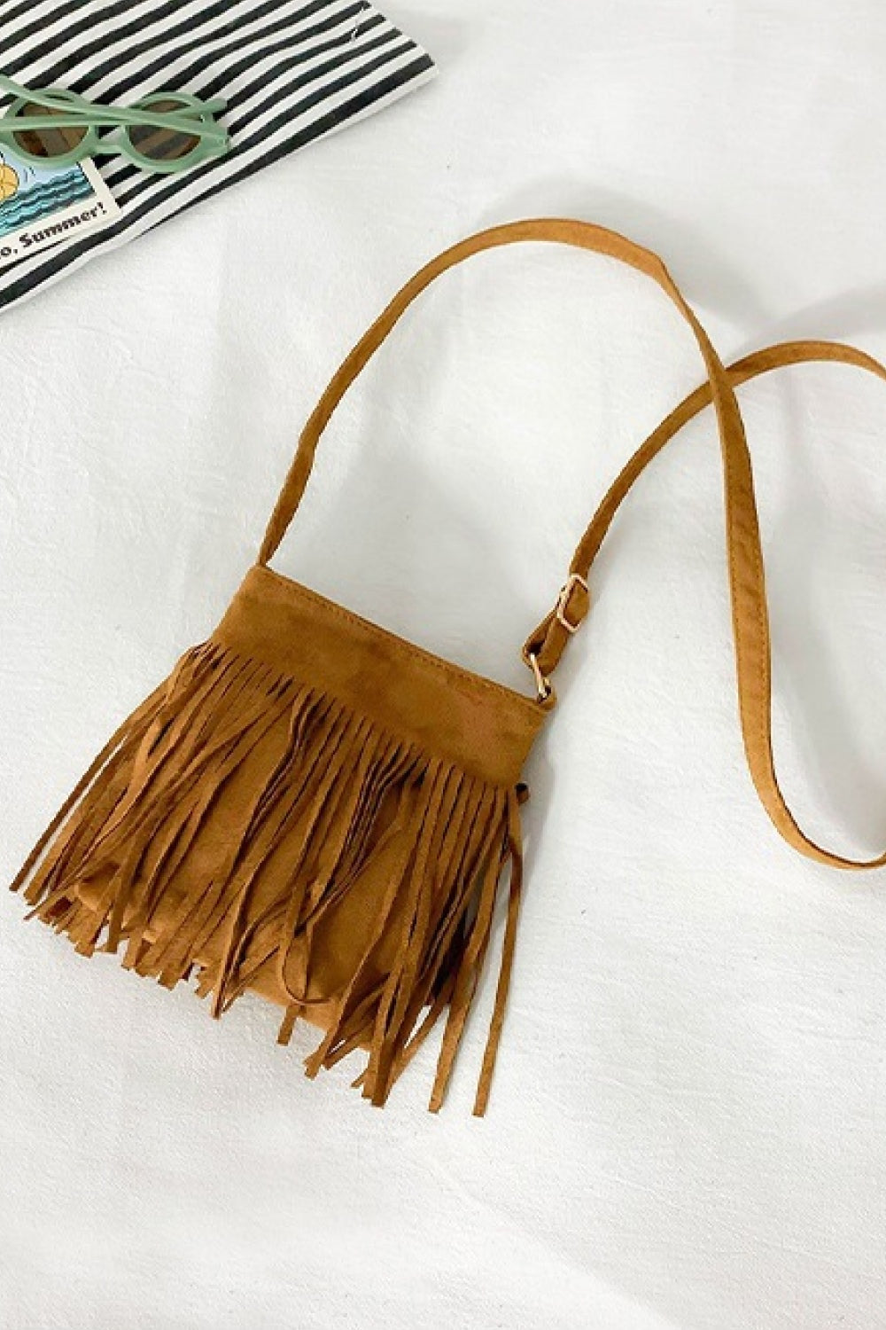 Small tan PU leather crossbody sling bag with a compact rectangular silhouette, adjustable strap, and long layered fringe detailing along the front.