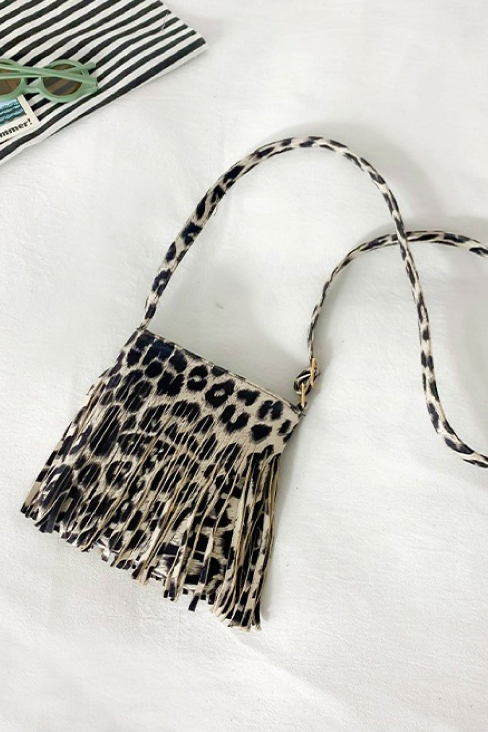 Small leopard-print PU leather crossbody bag with a compact rectangular silhouette, long adjustable strap, and dramatic fringe detailing along the front.