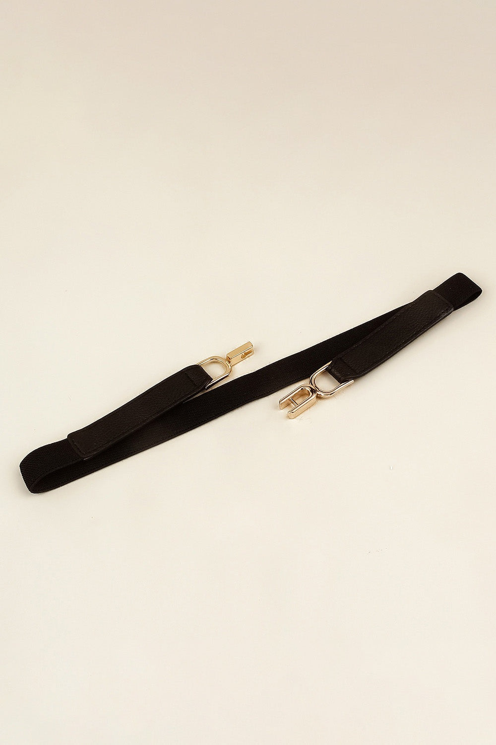 A slim black elastic belt with a textured PU finish, stitched edges, and a sculptural gold-tone alloy interlocking buckle.