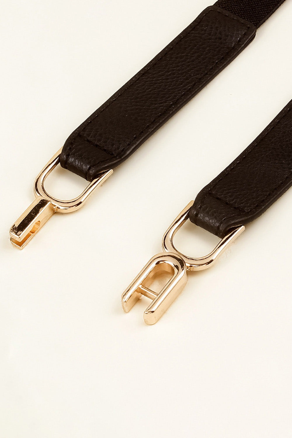 Dark brown elastic belt with textured PU panels, stitched edges, and polished alloy interlocking buckles in a slim, refined silhouette.