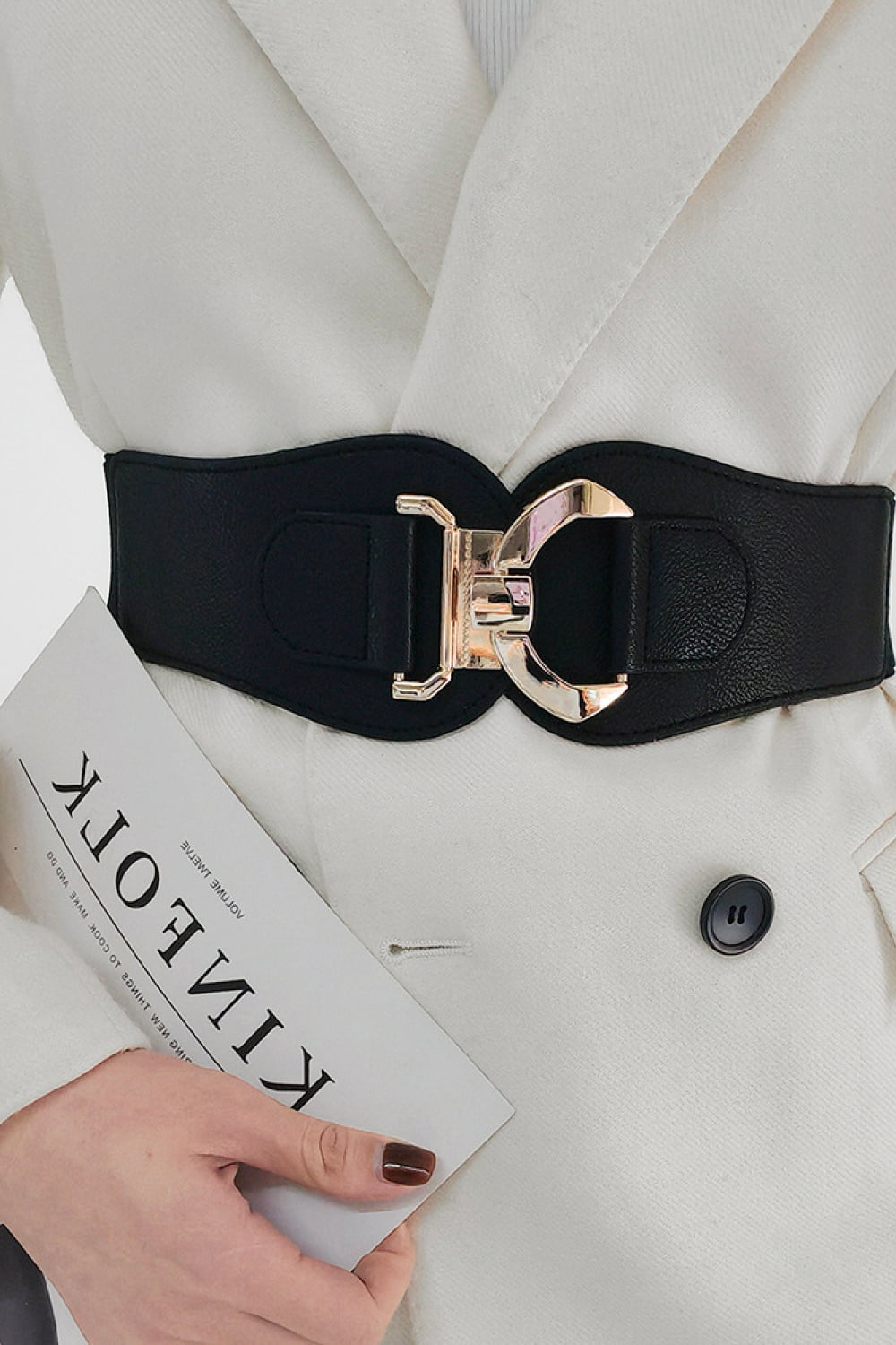 Close-up of a model wearing a broad black Alloy Buckle Elastic Belt over a white blouse, with a sculptural alloy buckle defining the waist.