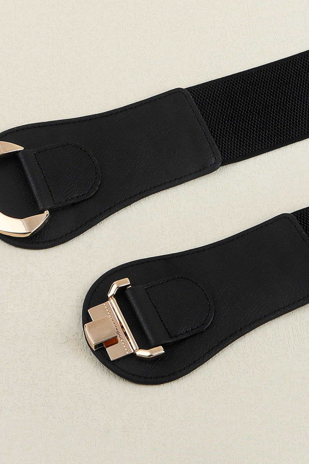 Close-up detail of a black Alloy Buckle Elastic Belt showing its broad PU-and-elastic band, curved stitched ends, and polished gold-tone alloy buckle.