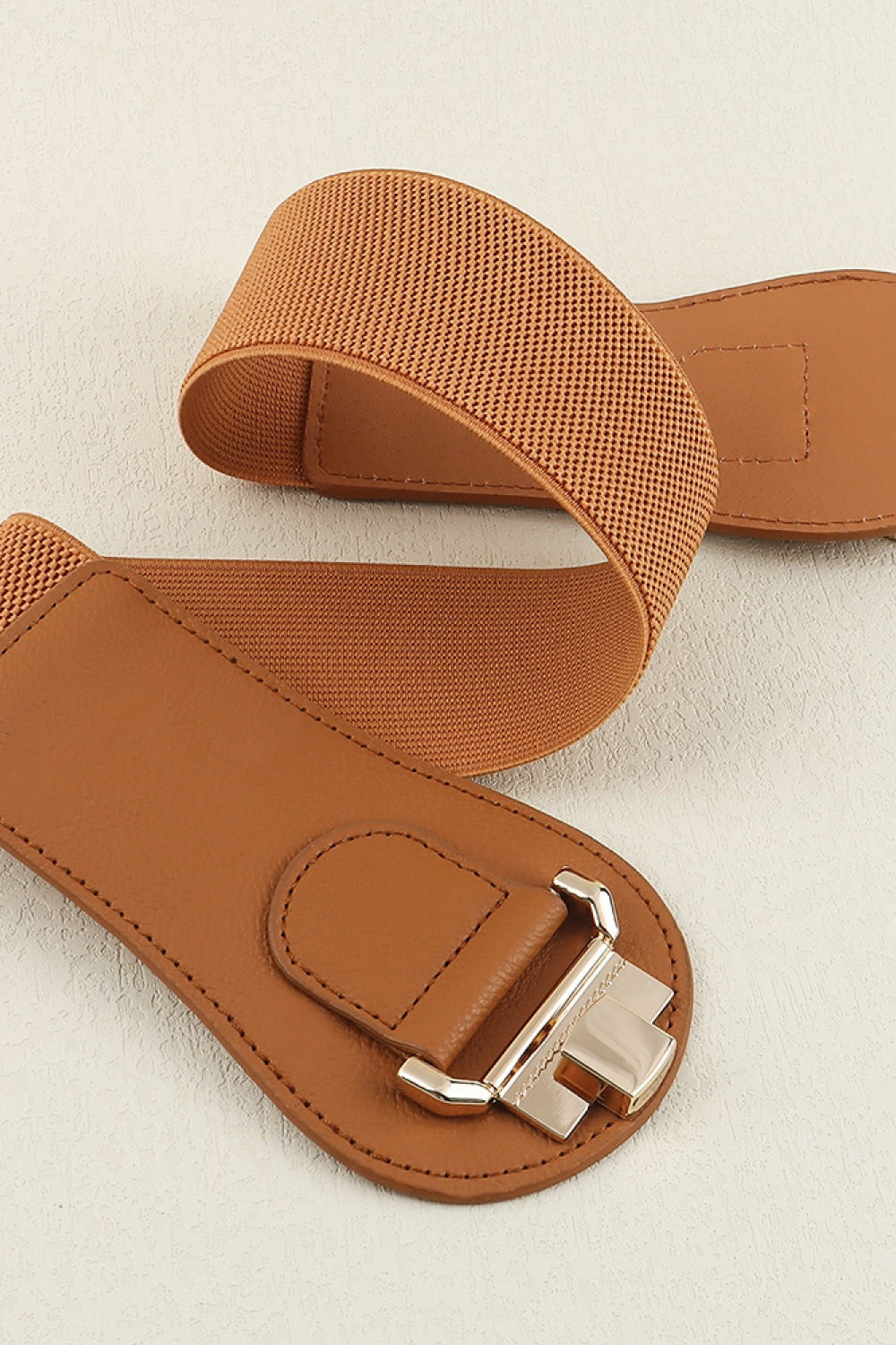 A brown Alloy Buckle Elastic Belt with a broad textured elastic panel, curved PU ends, neat stitching, and a polished sculptural alloy buckle.