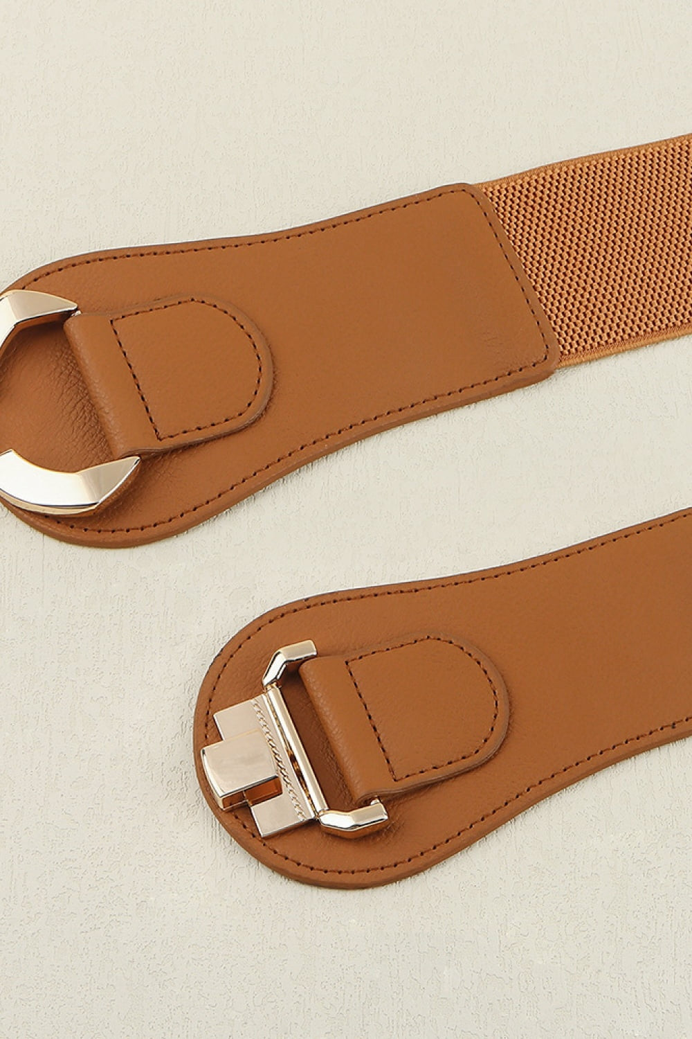 A broad brown PU and elastic belt with curved stitched ends and polished alloy buckles, showcasing its structured 2.4-inch silhouette.