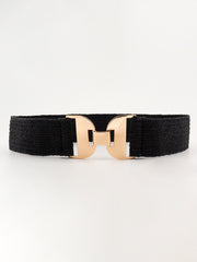 Black woven elastic belt with textured rubber ribs and a polished sculptural alloy buckle in a bold symmetrical silhouette.