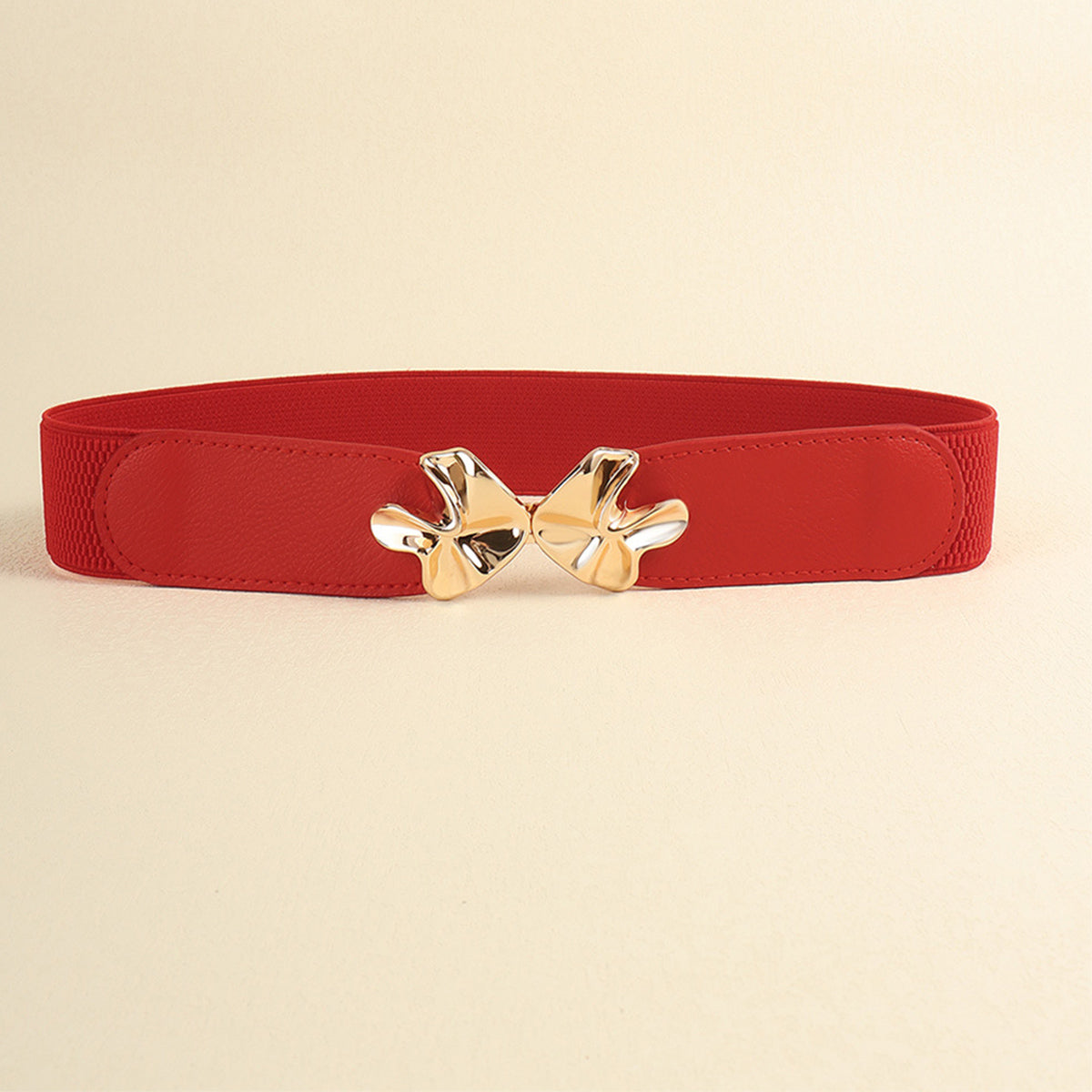 Red PU elastic belt with a wide silhouette, stitched edges, and a polished gold-tone alloy bow buckle at the center.