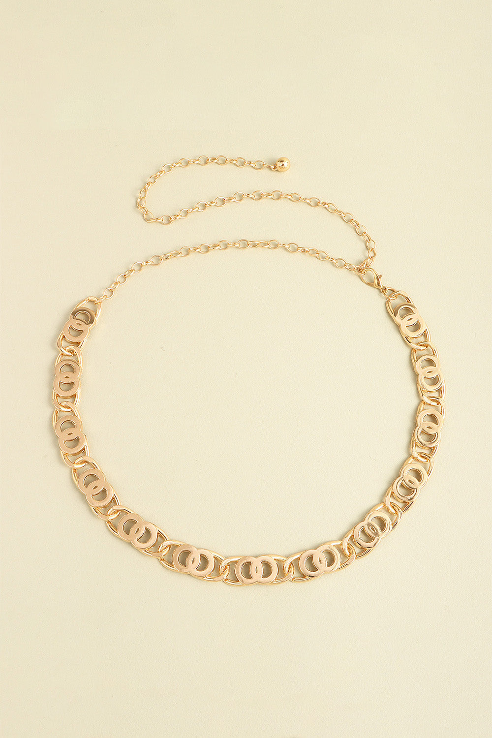 Gold-tone alloy lobster clasp belt featuring linked oval detailing, a slim chain design, and an extended chain for adjustable draping.