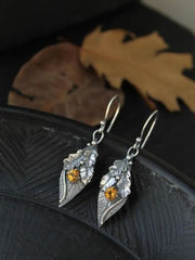 Leaf-shaped alloy drop earrings feature silver-toned botanical detailing and faceted rhinestones with warm amber accents for a graceful, sparkling finish.
