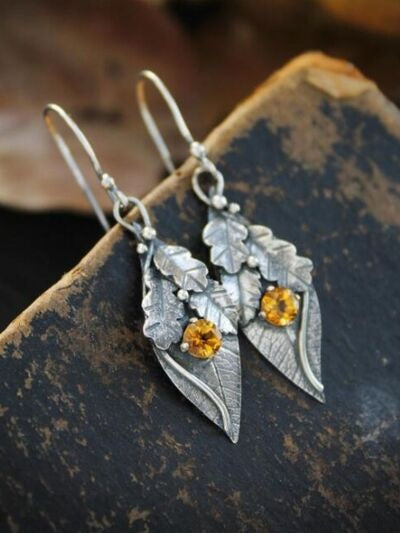 Silver-tone alloy leaf-shaped dangle earrings feature layered botanical leaves, faceted rhinestone accents, and slender hook closures for a graceful statement silhouette.