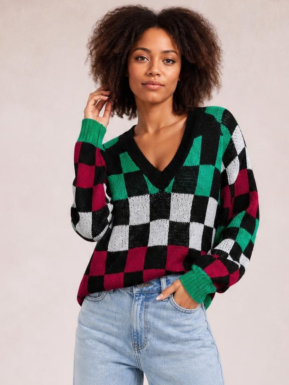 Model poses in a multicolor checkered V-neck sweater with voluminous lantern sleeves, ribbed green cuffs, and a relaxed silhouette.