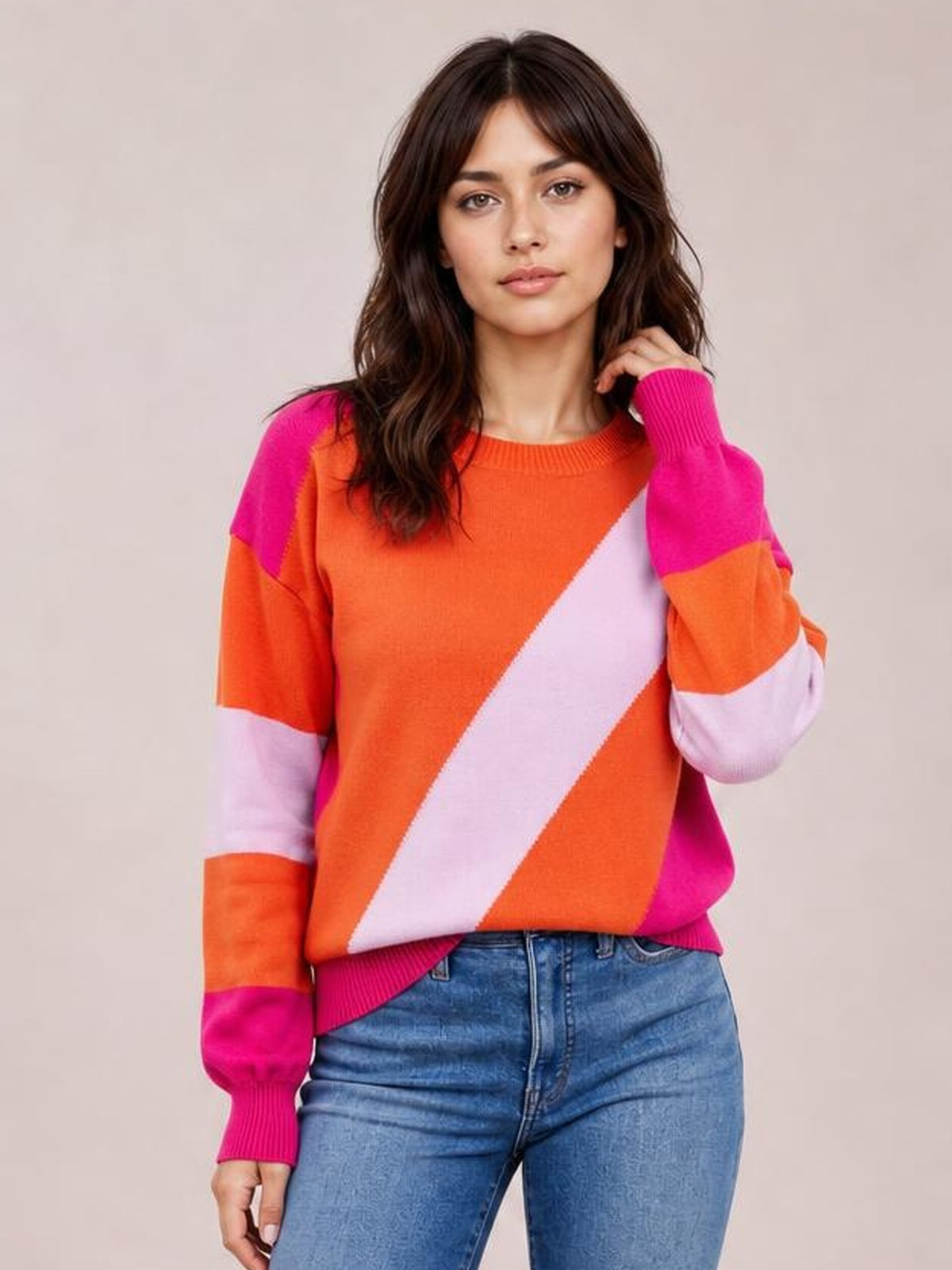Model poses in a color block ribbed round neck sweater with bright orange, pink, and lavender panels, long sleeves, and a regular silhouette.