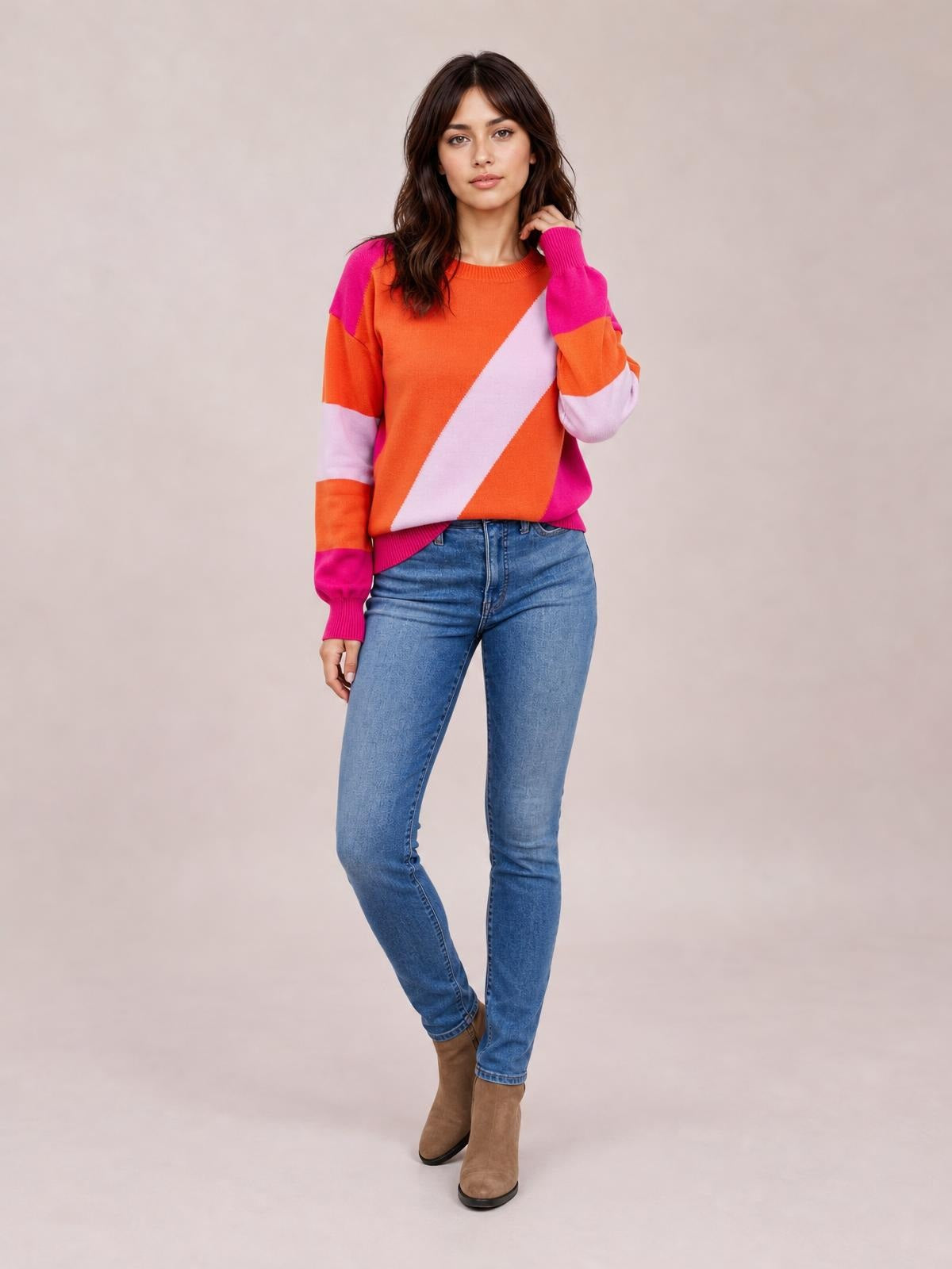 Model poses in a color block ribbed round neck sweater with orange, pink, and lavender panels, long sleeves, and a regular-length silhouette.