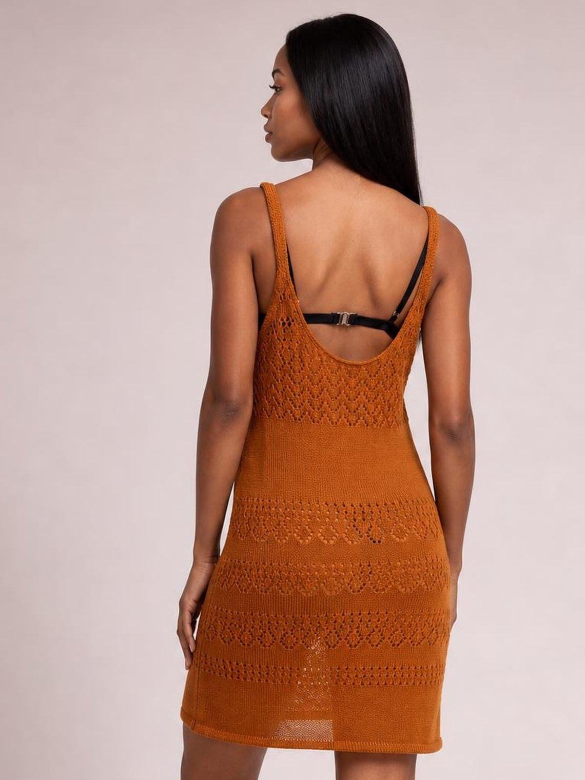 Model shown from behind in a rust-orange semi-sheer openwork cover-up with wide straps, a scoop back neckline, fitted silhouette, and patterned construction.