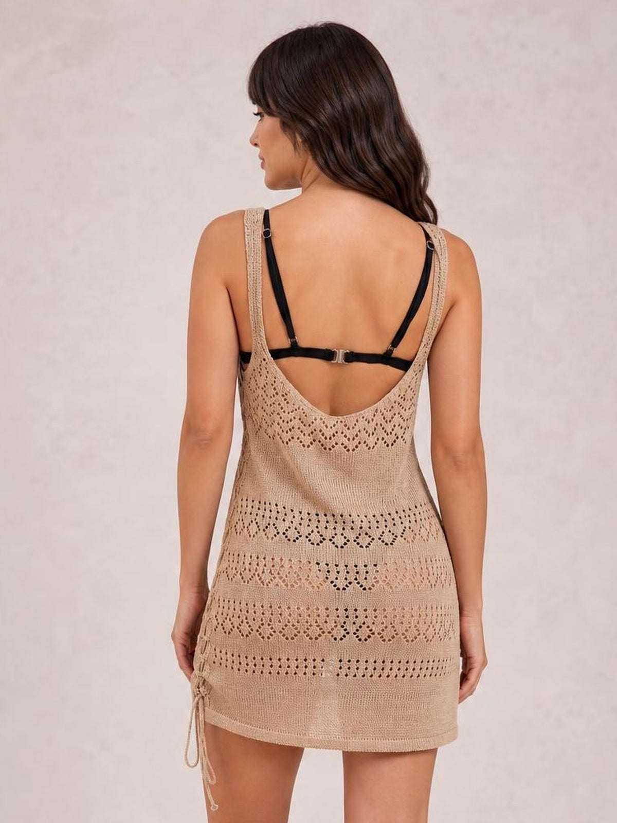 A model shows the back of a tan semi-sheer openwork scoop neck cover-up with slim straps, a fitted silhouette, and a short hem.