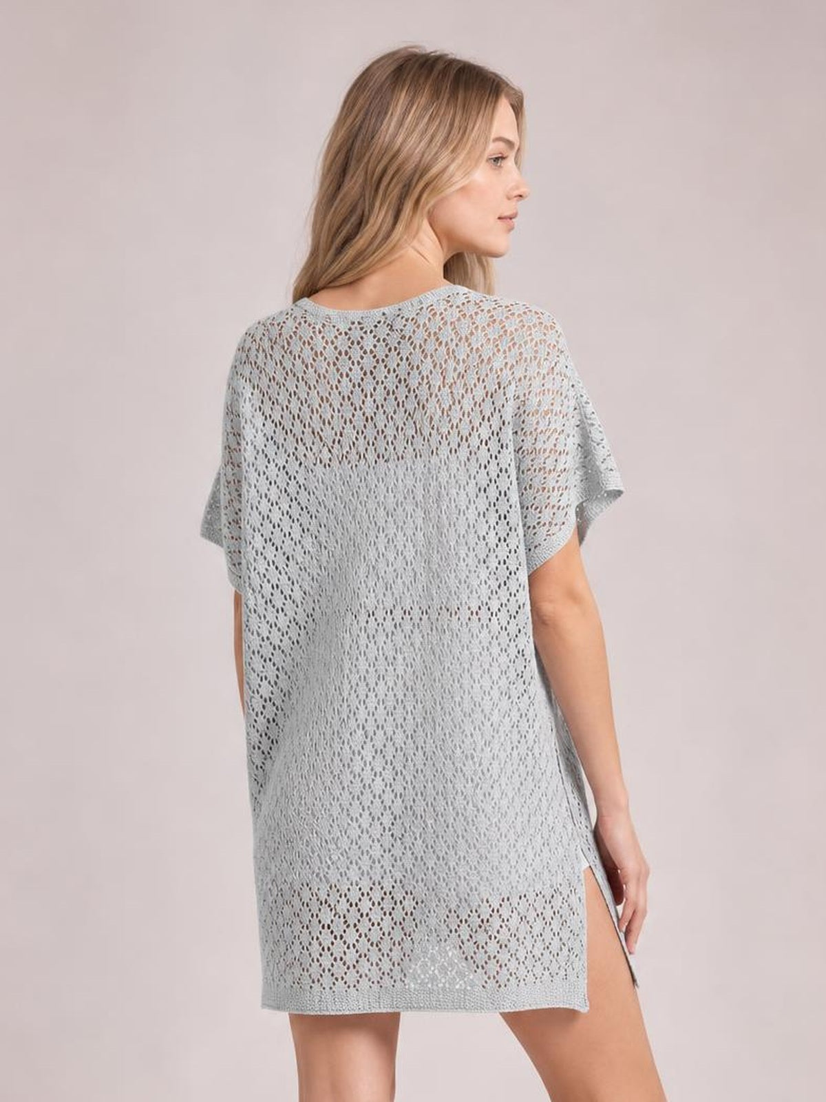 A model wears a light blue semi-sheer openwork cover up with short sleeves, a relaxed straight silhouette, and a visible side slit.
