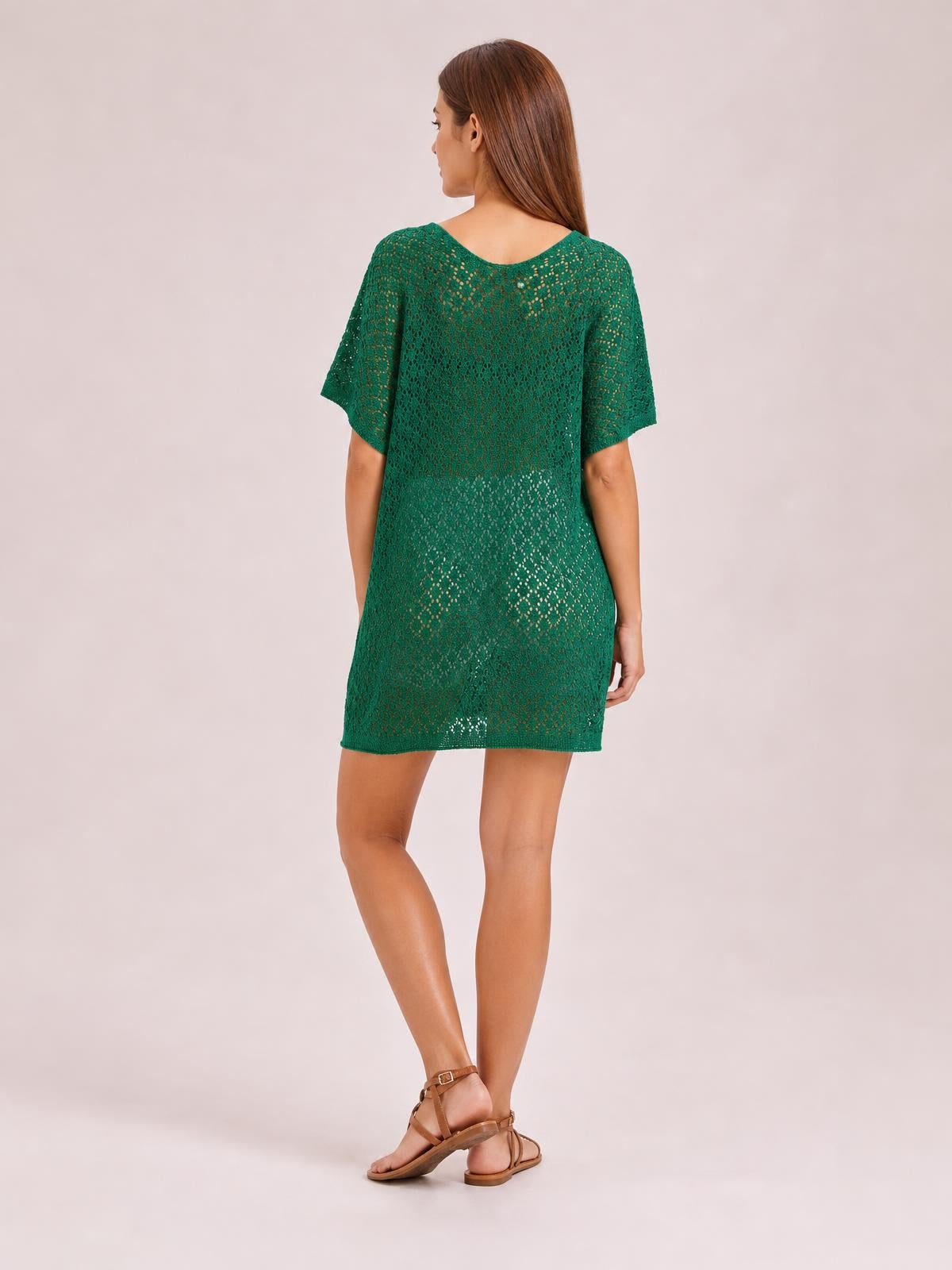A model poses turned away in a green semi-sheer openwork cover-up with a scoop neck, short sleeves, relaxed straight silhouette, and above-knee hem.