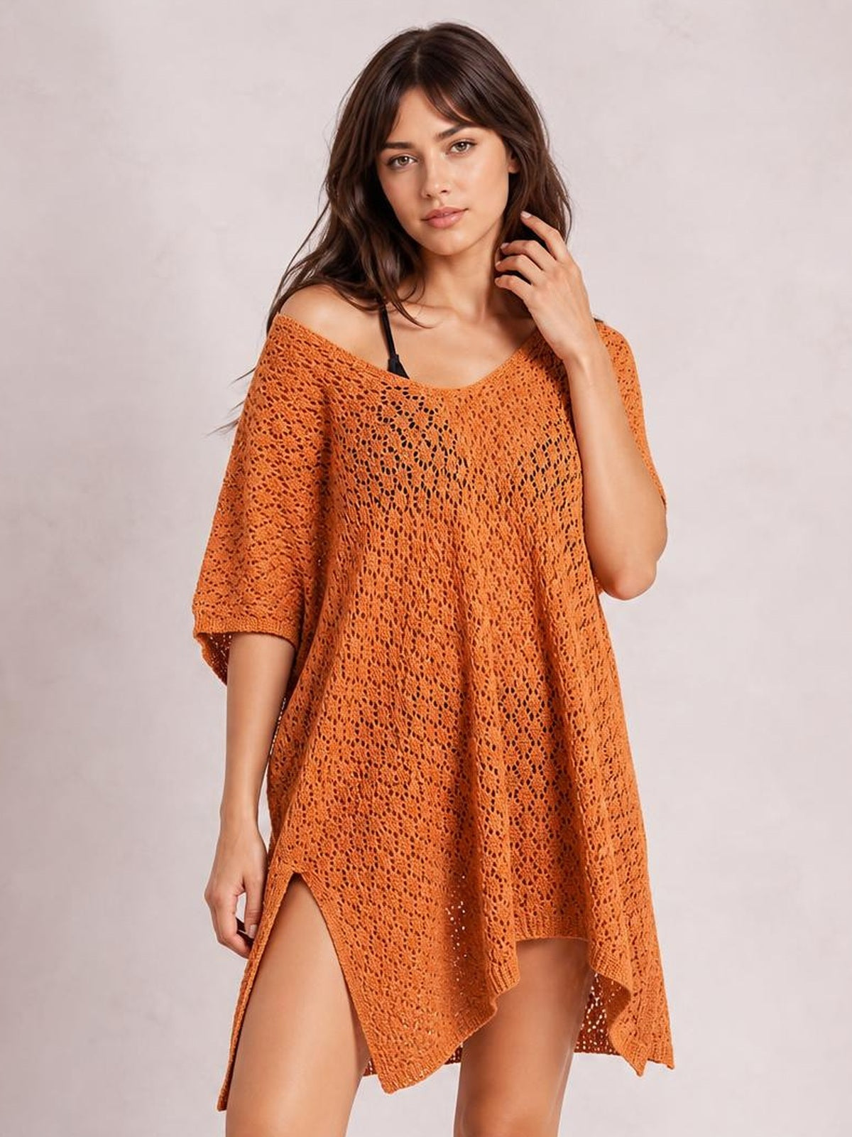 Model poses in an orange semi-sheer openwork cover up with a wide scoop neck, relaxed draped silhouette, short sleeves, and slit sides.
