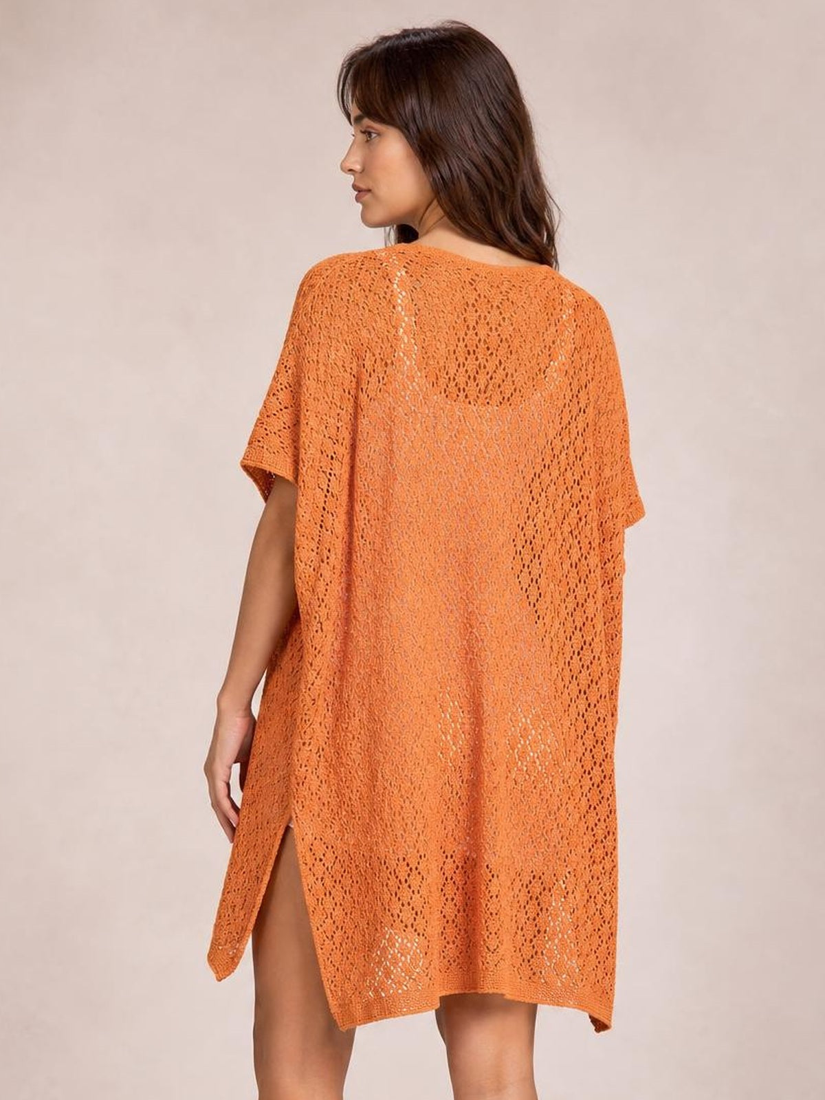 Model poses in an orange semi-sheer openwork cover up with a loose silhouette, short sleeves, scoop neckline, and side slit.