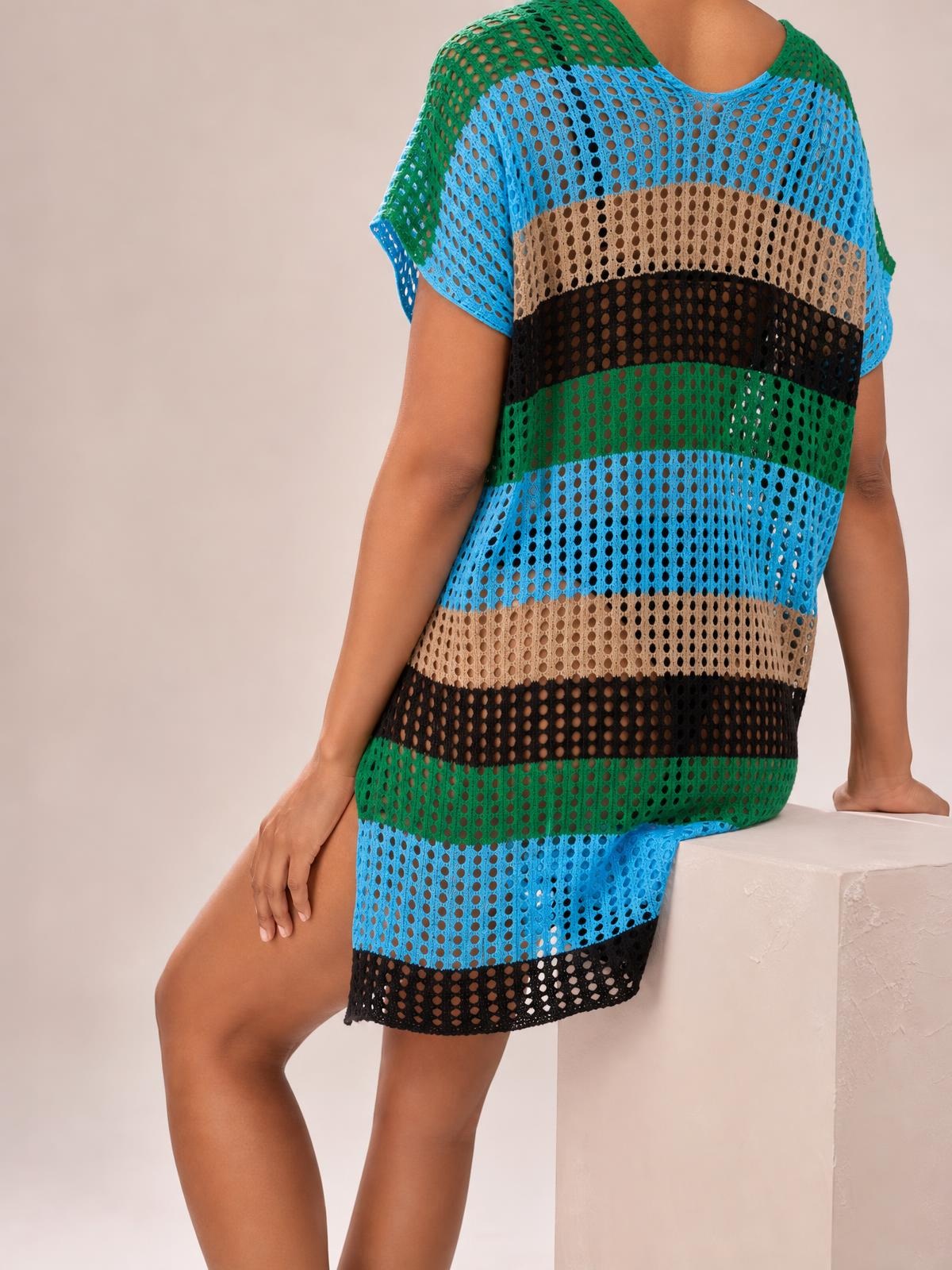 Model seated in a relaxed pose wears a loose, semi-sheer openwork striped cover-up with short sleeves and blue, green, tan, and black bands.