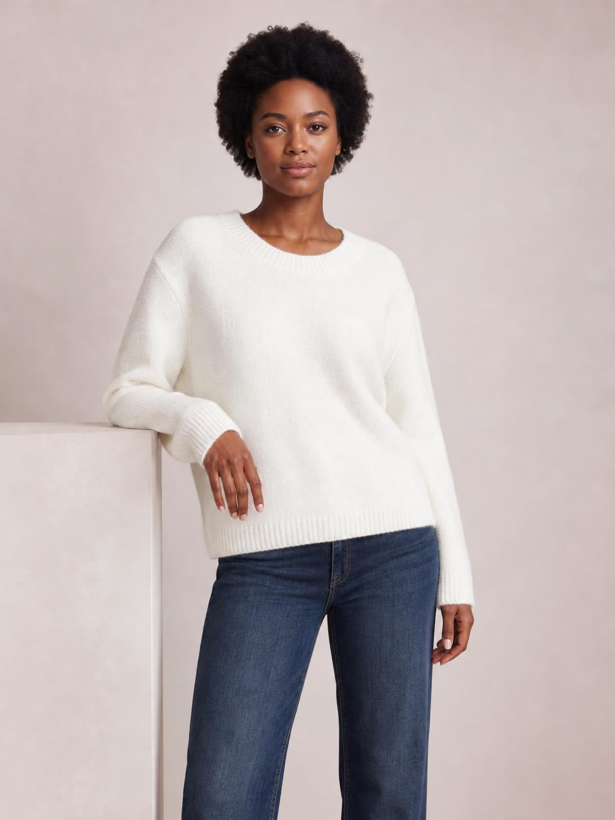 Model wears a solid white ribbed sweater with a round neck, long regular sleeves, ribbed cuffs and hem, and a relaxed regular-length silhouette.