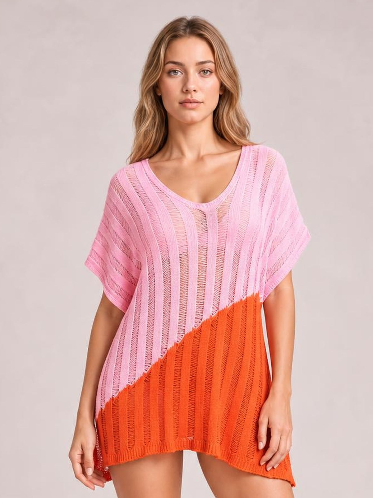 A model faces forward in a sheer pink and orange color-block cover-up with a V-neck, relaxed short sleeves, vertical open-knit construction, and a loose silhouette.