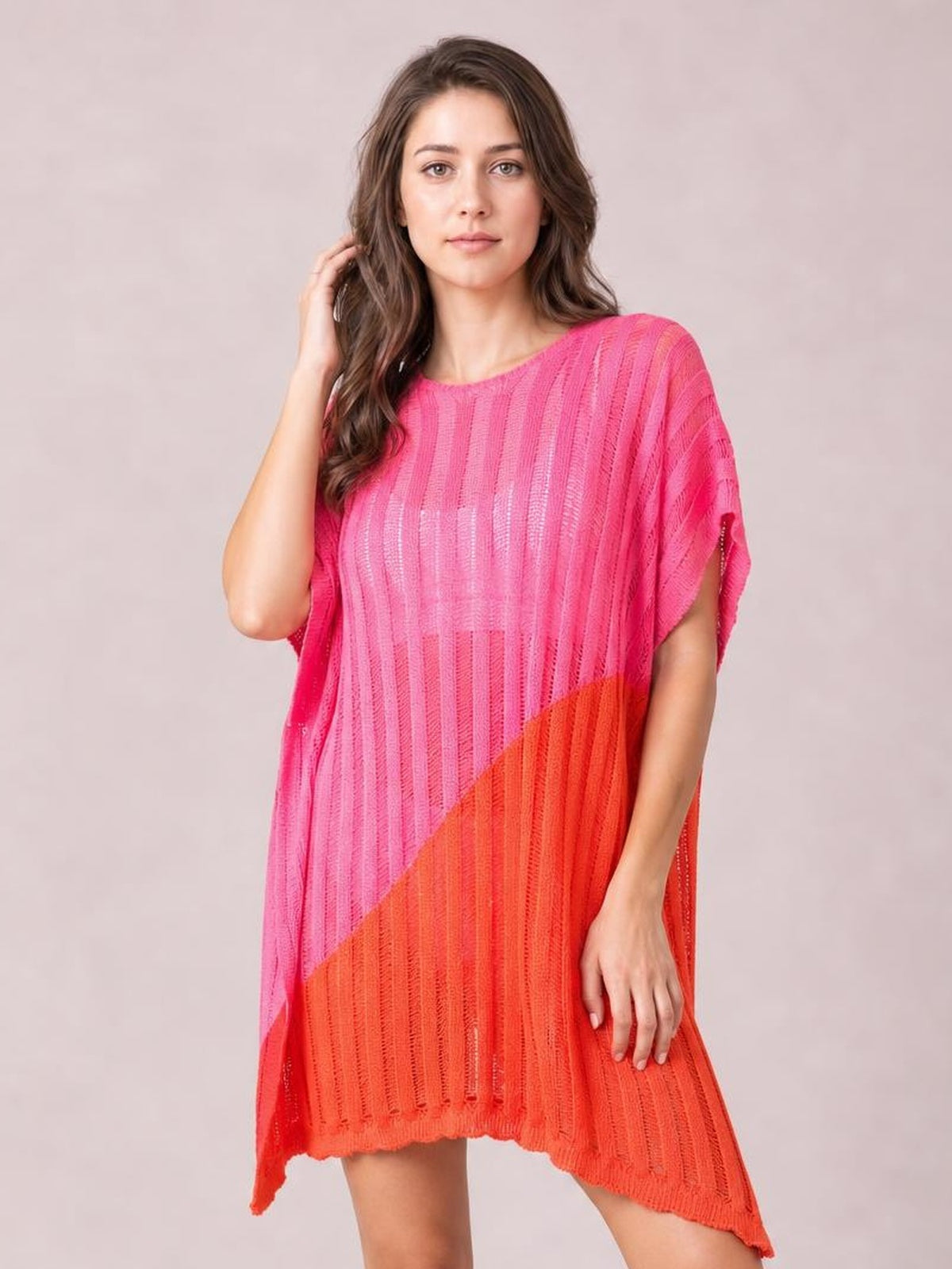Model wears a loose sheer pink and orange color block cover up with vertical open-knit texture, side slit, short sleeves, and a high-low hem.