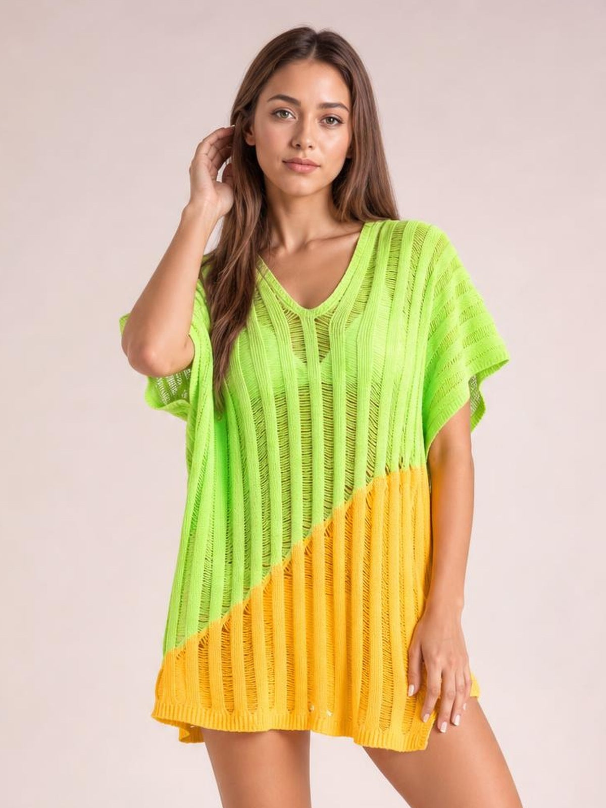 Model poses with one hand near her hair in a sheer lime green and yellow color-block V-neck cover-up with a loose silhouette and short sleeves.