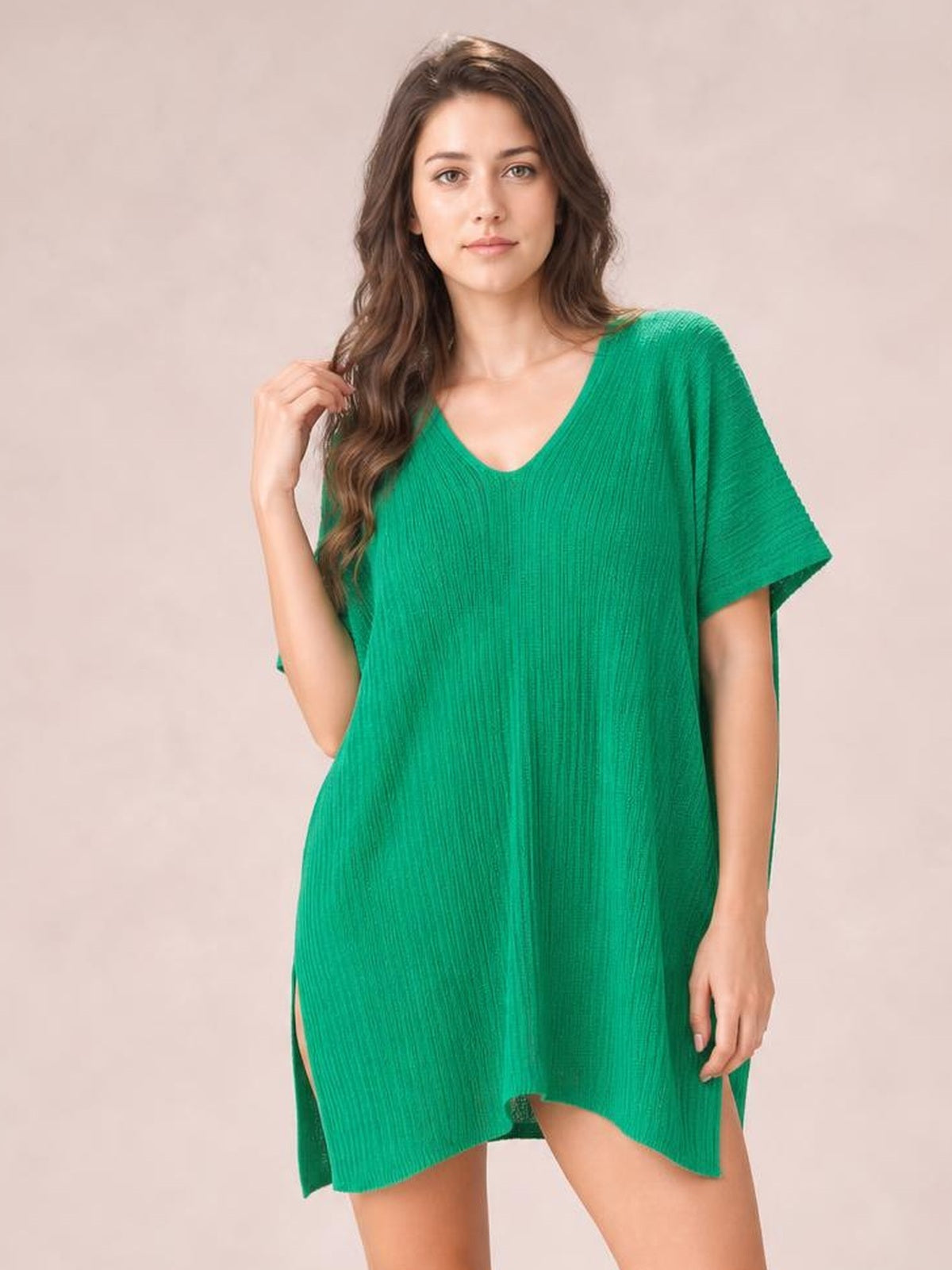 A model poses in a loose green semi-sheer cover up with a V-neck, short sleeves, textured fabric, side slits, and an oversized tunic silhouette.