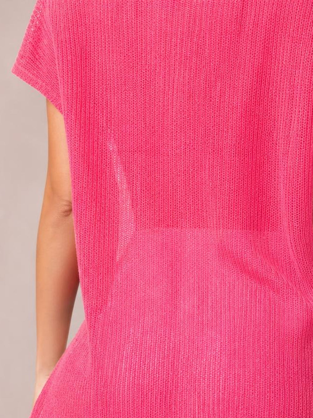 A model wears a bright pink semi-sheer cover up with short sleeves, a relaxed stretchy silhouette, and a visible side slit.