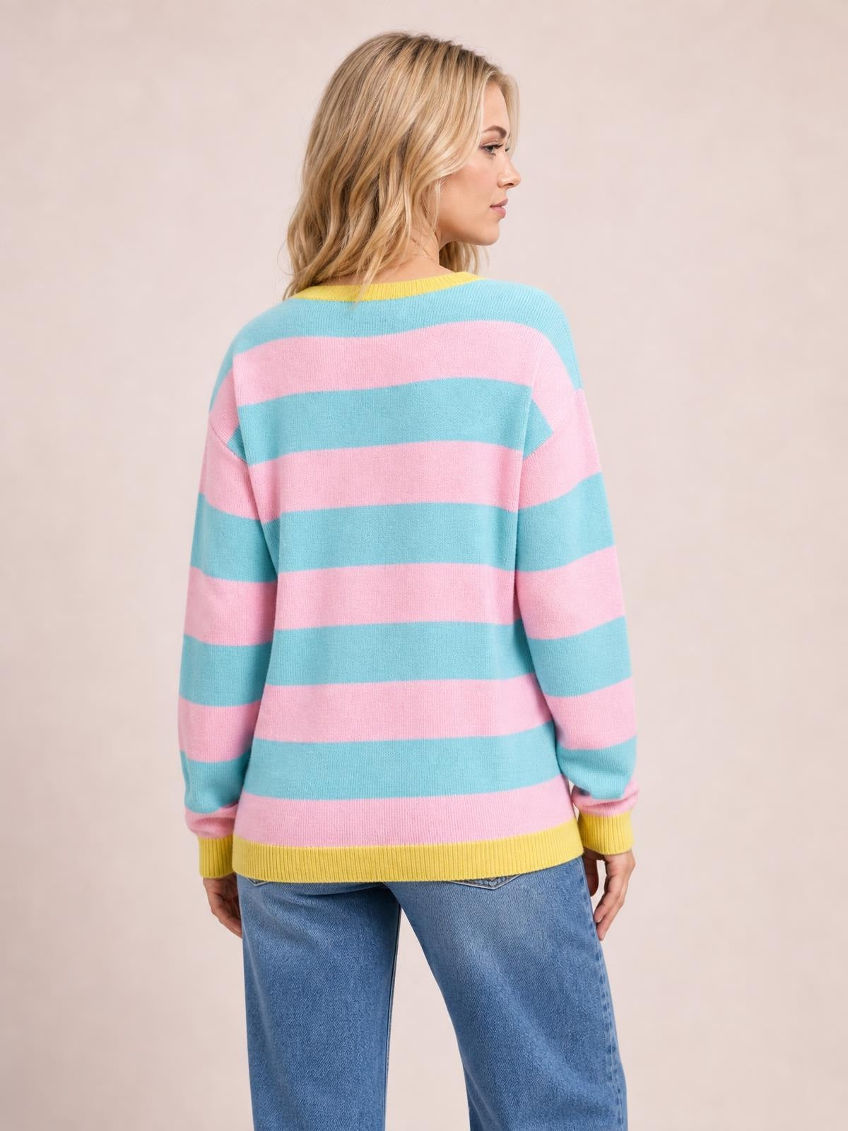 Model shown from behind wearing a pastel striped round neck dropped shoulder sweater with a relaxed silhouette, long sleeves, and ribbed yellow cuffs and hem.