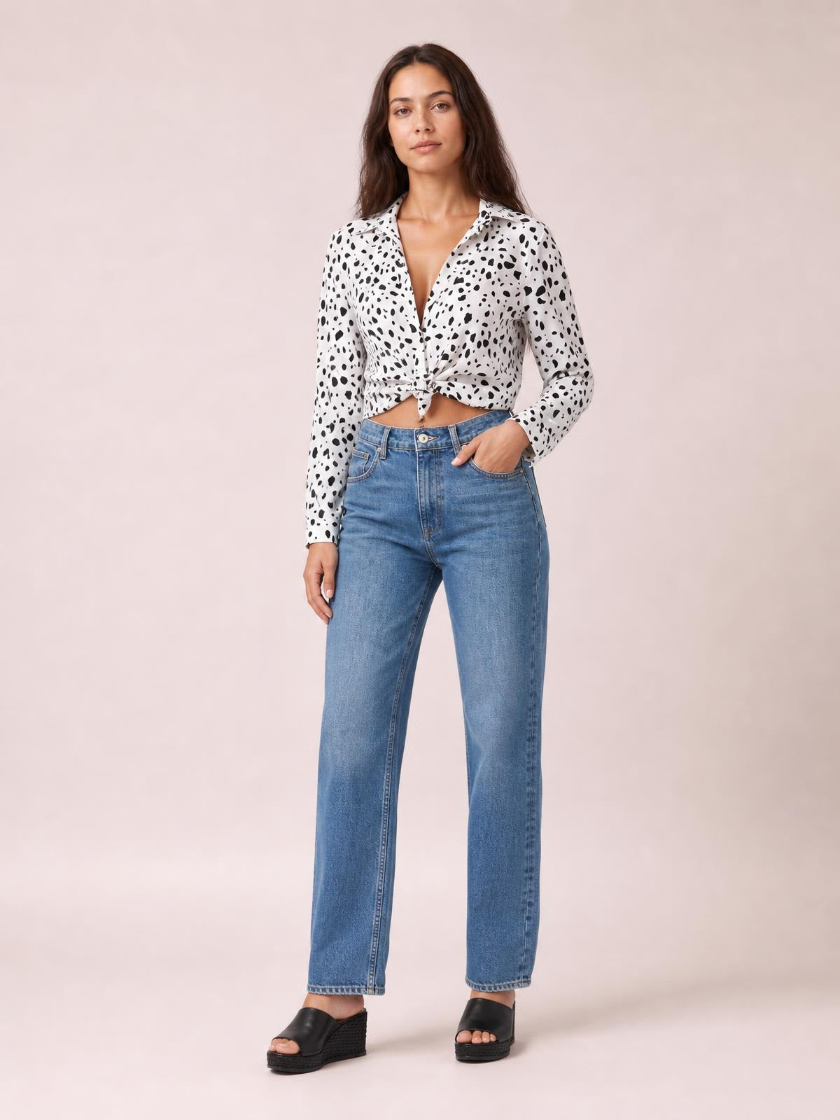 A model stands in a white and black animal print button-up shirt with a collared neckline, long sleeves, and a tied waist creating a cropped silhouette.