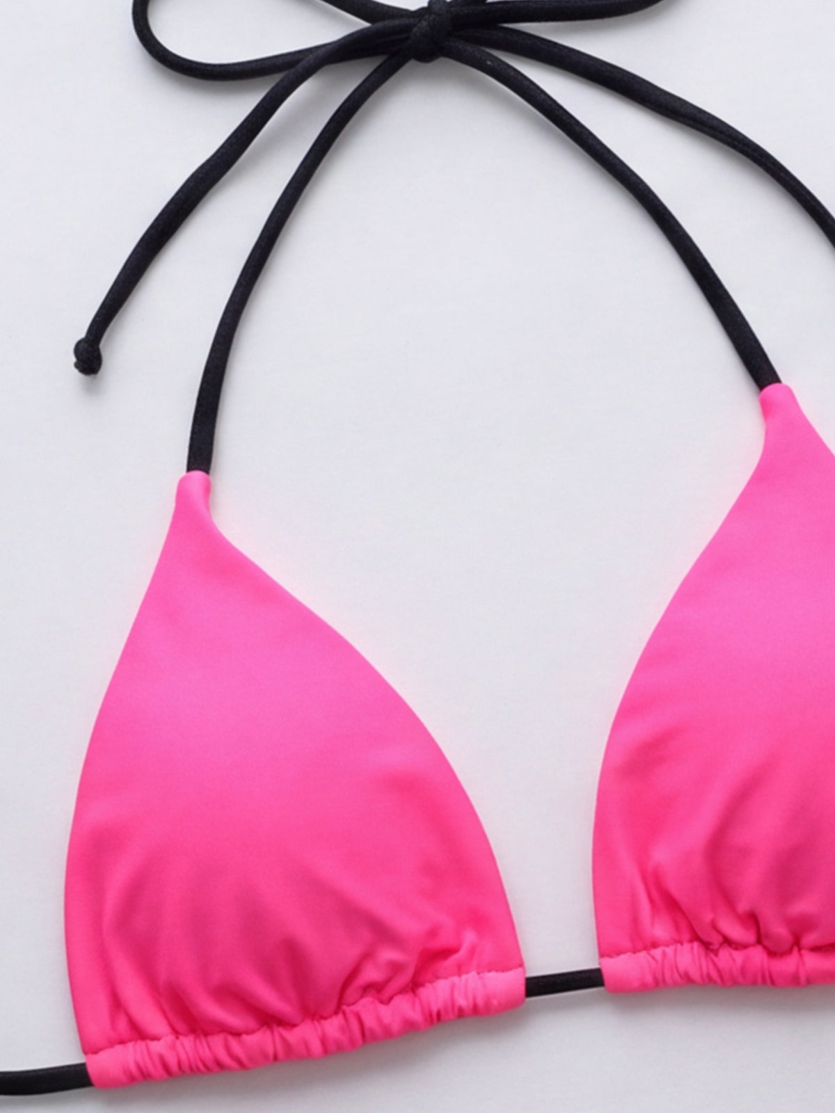 Bright pink triangle bikini top with black tie straps and a gathered underbust band, shown flat to highlight its simple string construction.