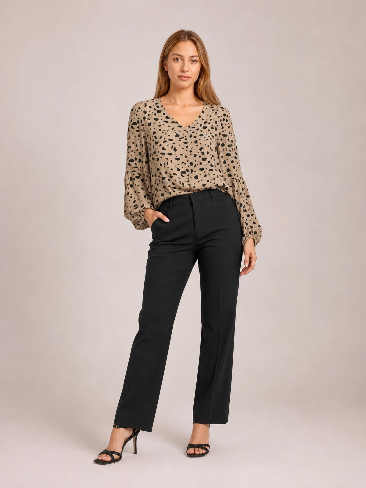 Model wearing a tan and black animal print V-neck high-low blouse with long balloon sleeves, a relaxed silhouette, and one hand in her pocket.