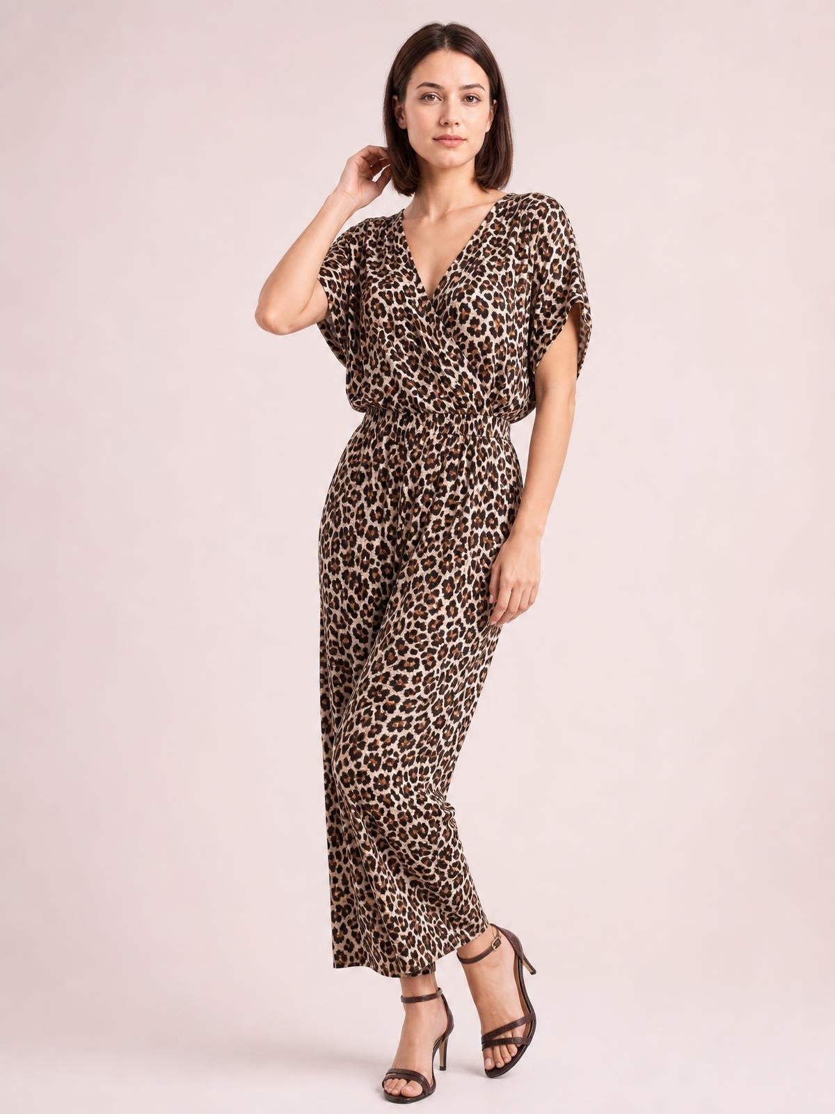 Model poses in a leopard-print wide-leg jumpsuit with a V-neck, short sleeves, elasticized waist, flowing cropped silhouette, and side pockets.