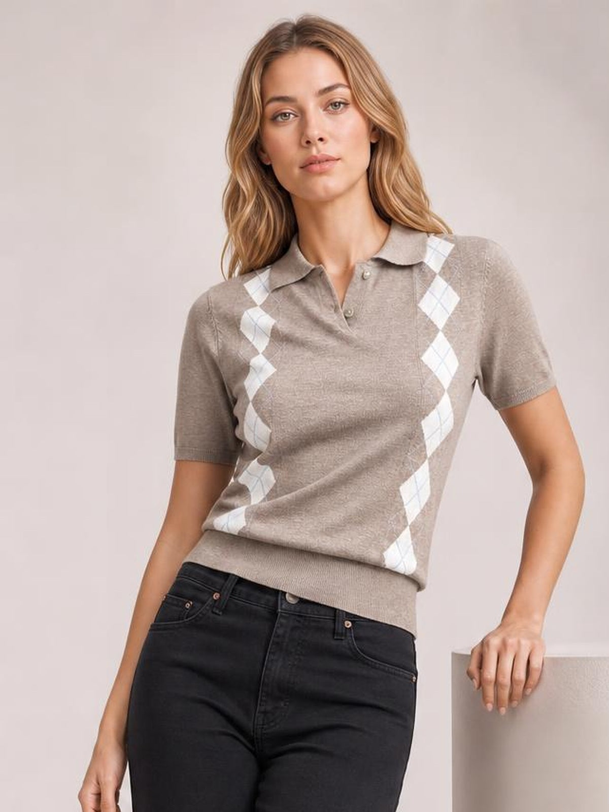 A model poses in a taupe short sleeve sweater with a white argyle pattern, polo collar, button placket, and ribbed hem in a relaxed silhouette.