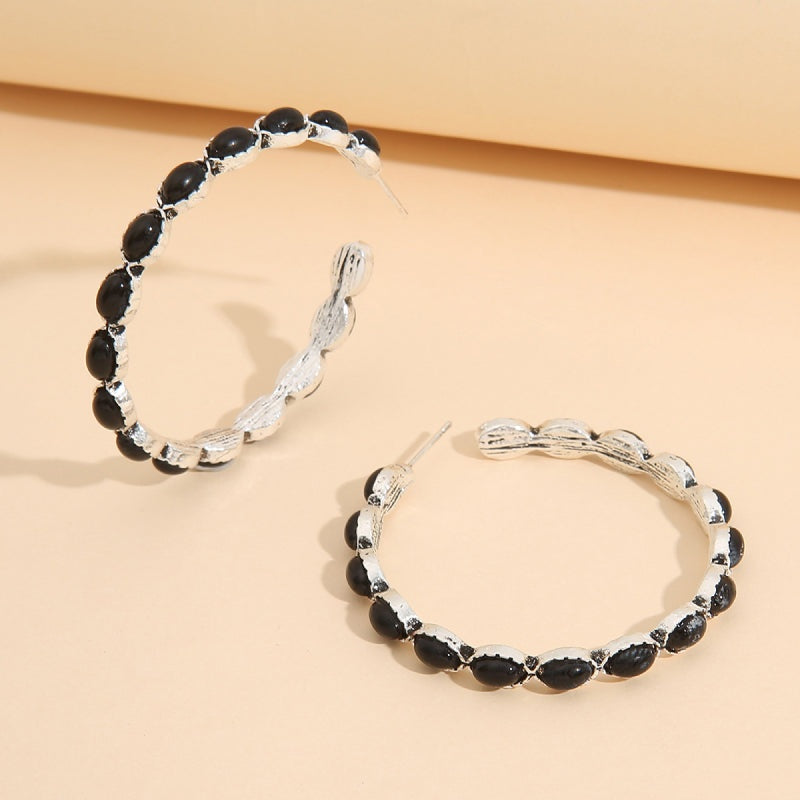 Silver-tone C-hoop earrings feature a rounded open silhouette with textured twisted bands and dark oval bead detailing along the outer edge.