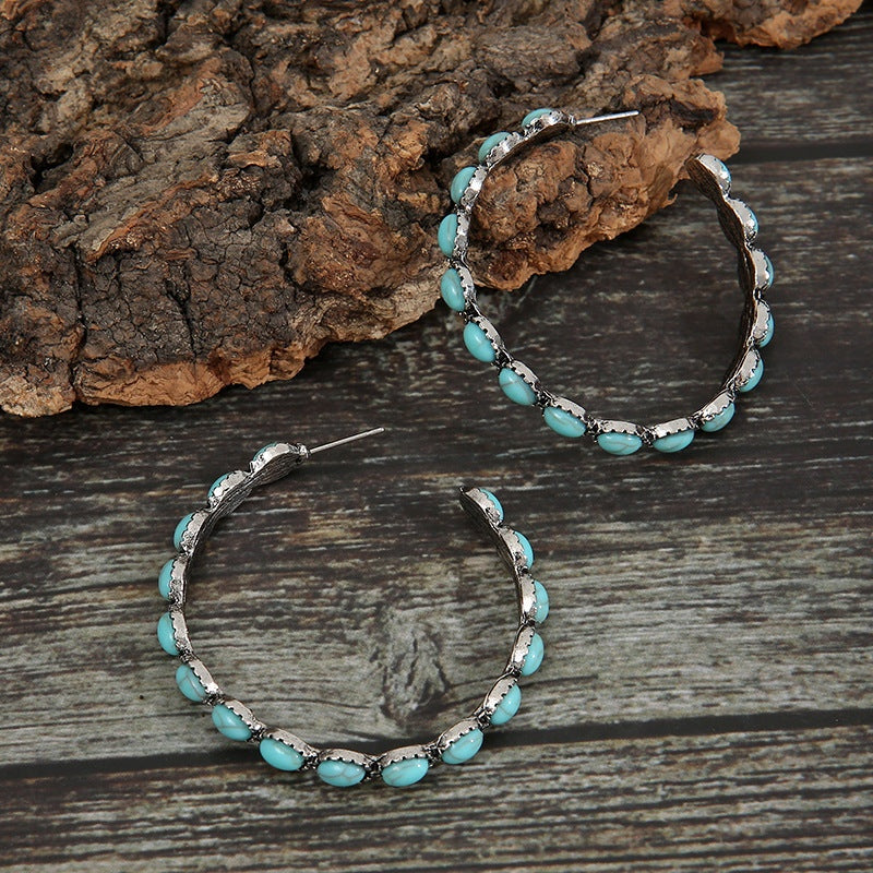 A pair of 2-inch alloy C-hoop earrings with open curved silhouettes, silver-tone detailing, and artificial turquoise accents along the outer edges.