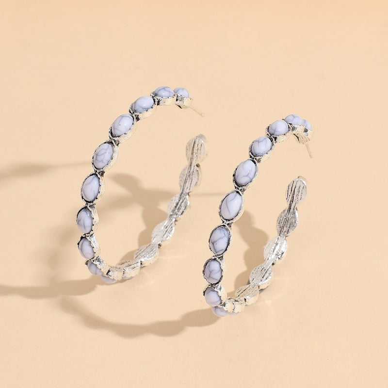 Large artificial turquoise C-hoop earrings feature a curved alloy silhouette with oval stone accents and textured silver-tone construction.