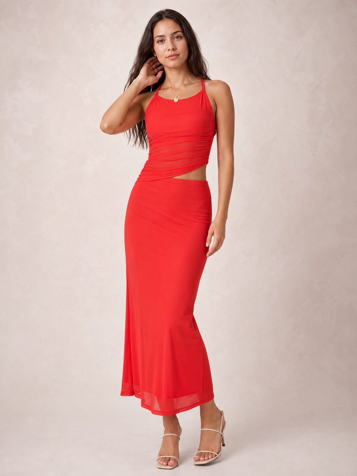 A model poses in a red asymmetrical cutout sleeveless maxi dress with twisted ruching, a figure-skimming silhouette, and an ankle-length skirt.